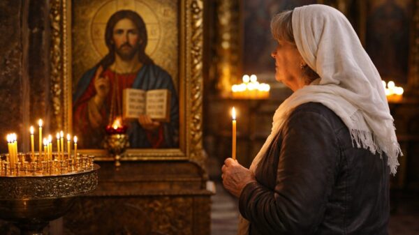 O femeie se afla in biserica si se roaga in fata icoanei Mantuitorului stand cu lamanarea in mana.