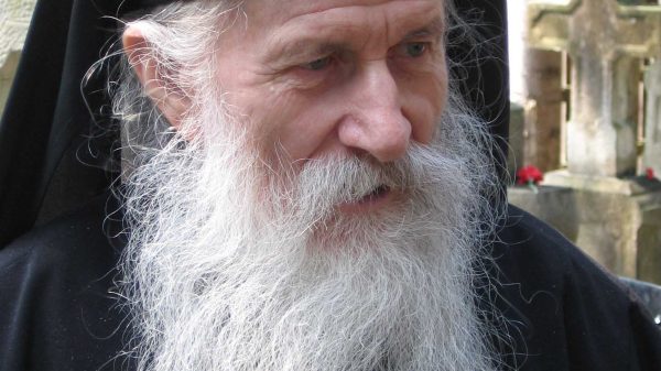 Un calugra ortodox cu barba lunga imbracat in vesminte monahale.